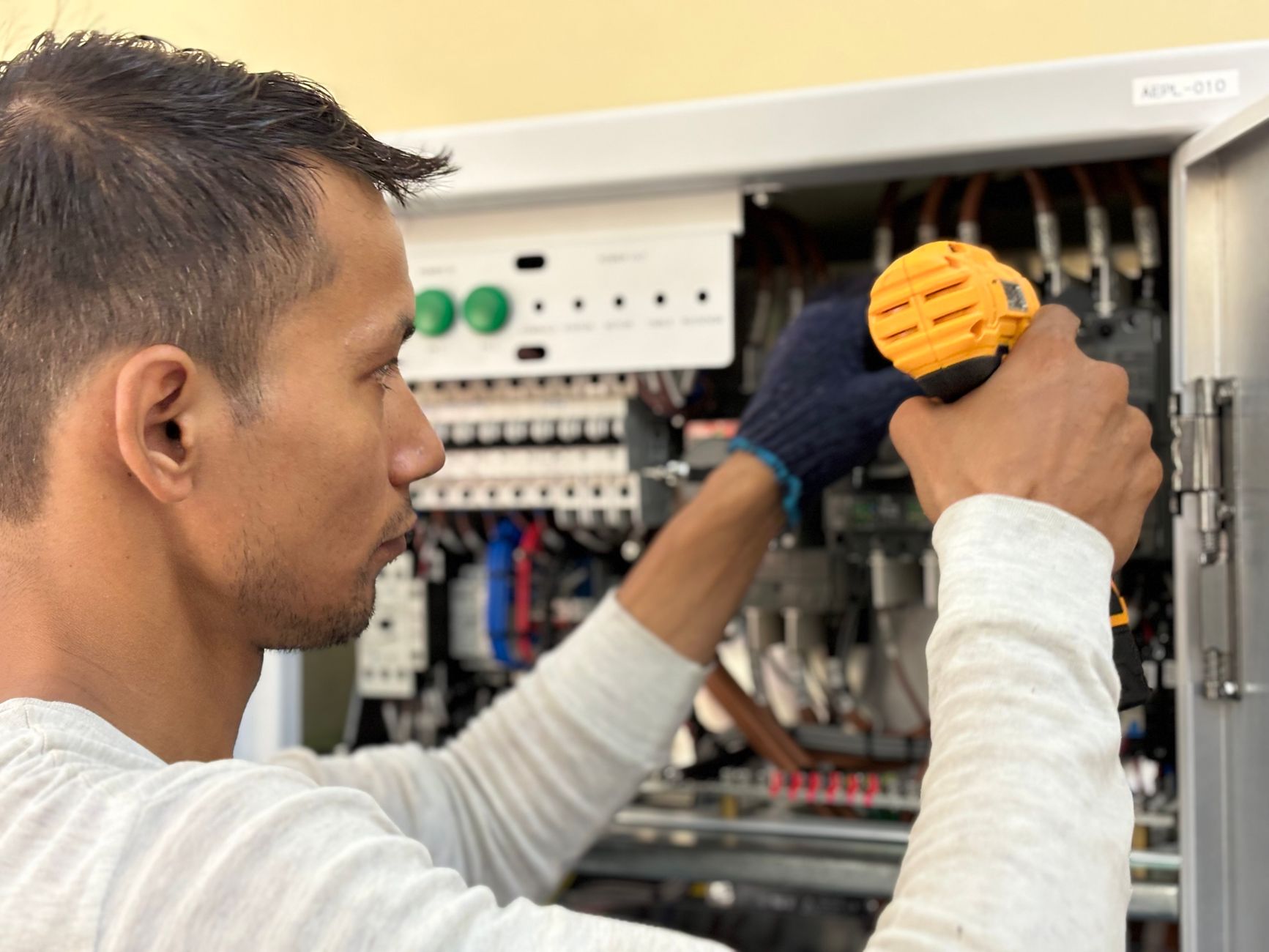 technicien posant un panneau publicitaire sur mesure sur la façade d’une entreprise, avec contrôle de l’alignement et des fixations