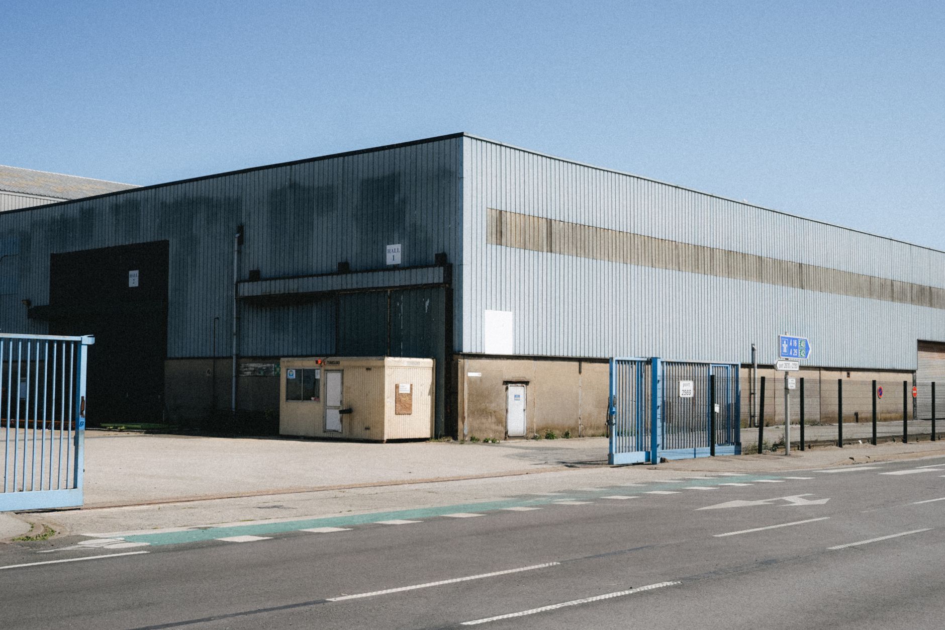 Technicien prenant les mesures d’une façade commerciale à Dunkerque avant l’installation d’un store, avec vitrine et enseigne visibles